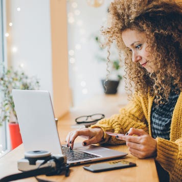 woman holding credit card and typing on laptop computer