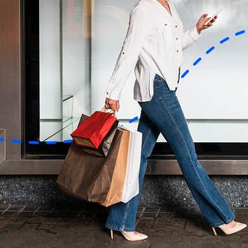 woman walking in a business district with multiple paper shopping bags