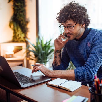 man talking on the phone while working on his computer