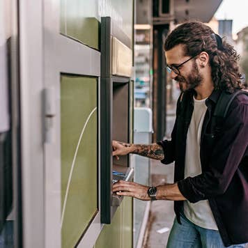 man using an atm on the street