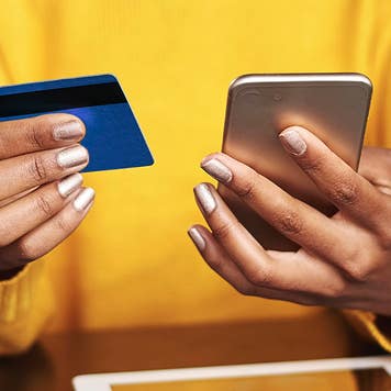 close up of a woman holding a smartphone and a credit card