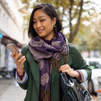 woman looking at her phone while walking outside