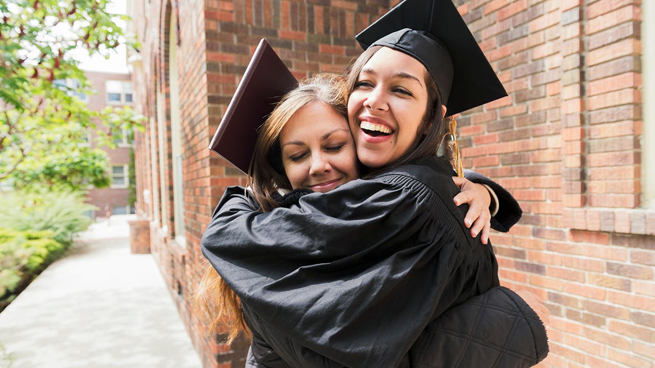 mother hugs daughter wearing a graduation hat
