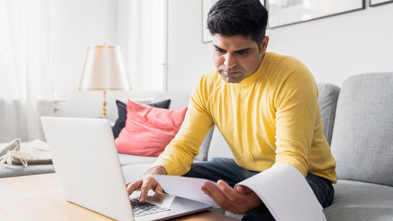 man reviewing paperwork while paying bills online