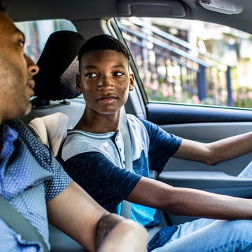 teenage son driving with his father
