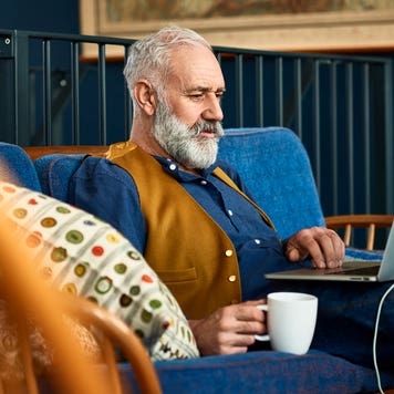 man sitting on the couch at home working on his laptop