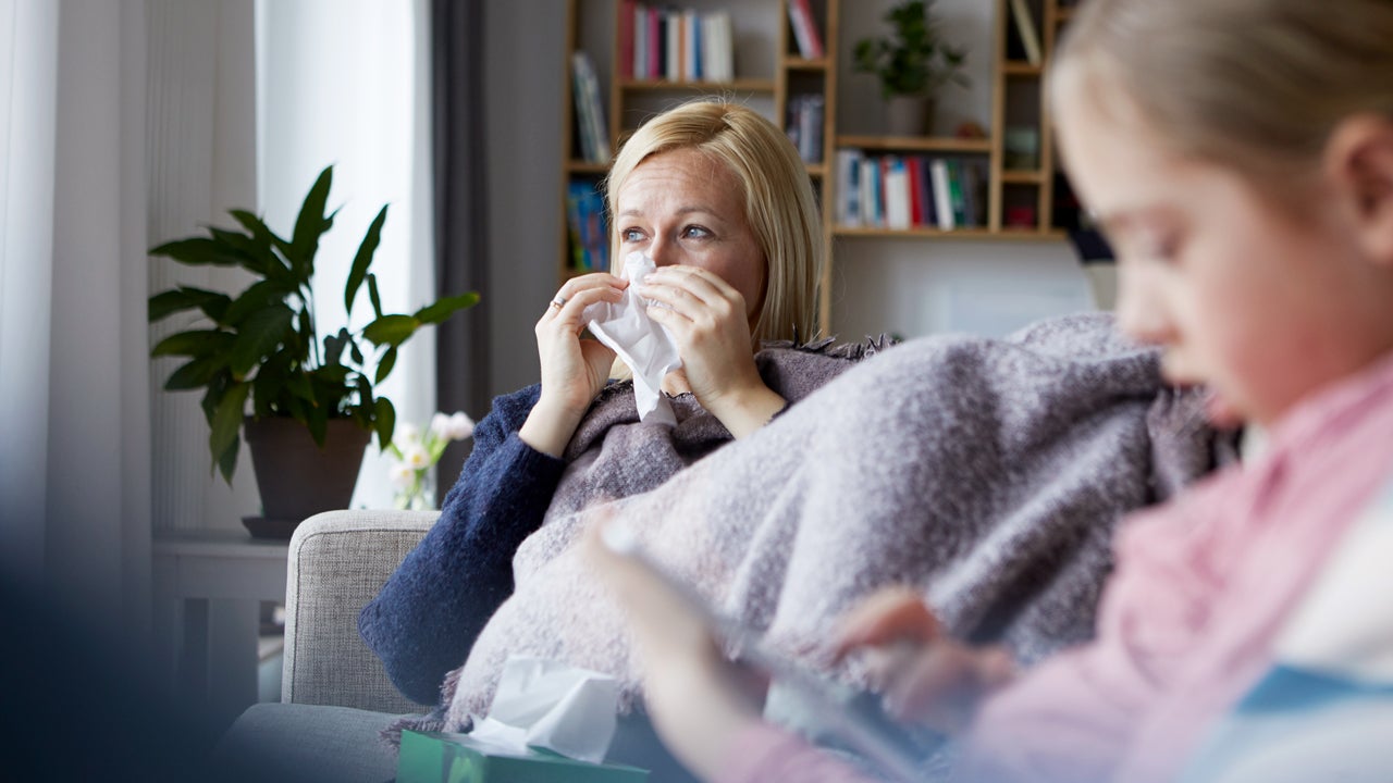 sick mother sitting on the couch next to her daughter