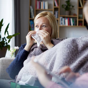 sick mother sitting on the couch next to her daughter
