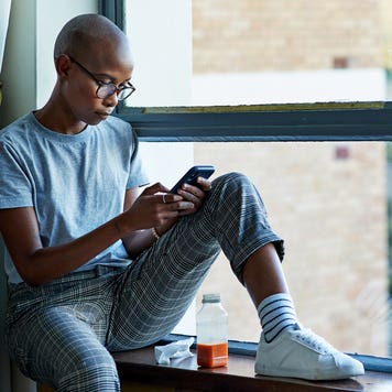woman sitting by the window and looking at her phone
