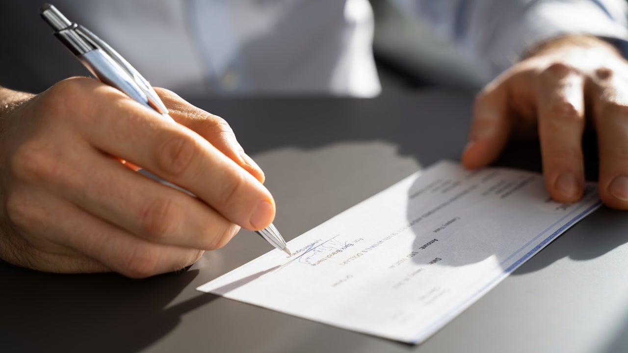 close up of hands signing a check