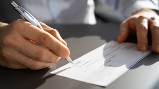 close up of hands signing a check