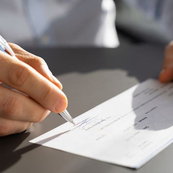 close up of hands signing a check