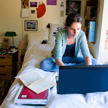 College student works on laptop in a dorm room