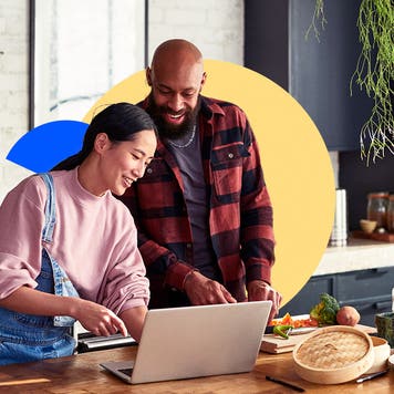 Two people looking at a laptop featuring illustrated graphics