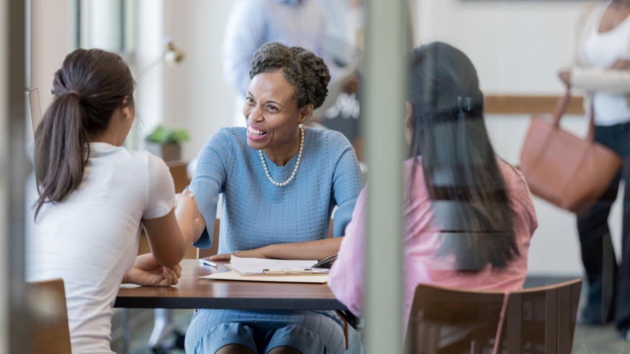 Two women meet with a Black credit union advisor.