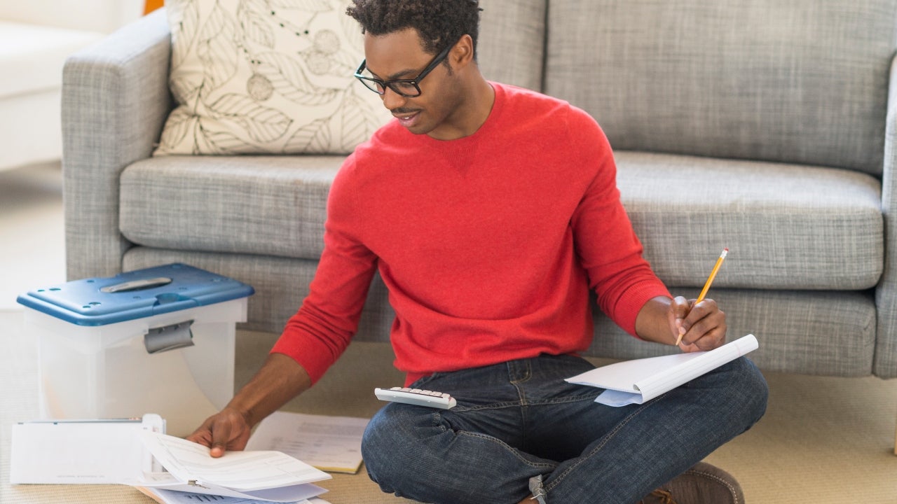 Man sits on the floor and works on paperwork