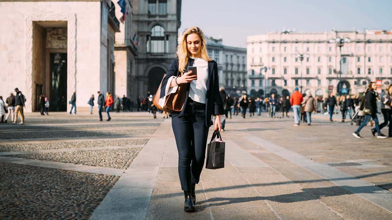 women on her phone walking on a sidewalk