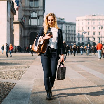 women on her phone walking on a sidewalk