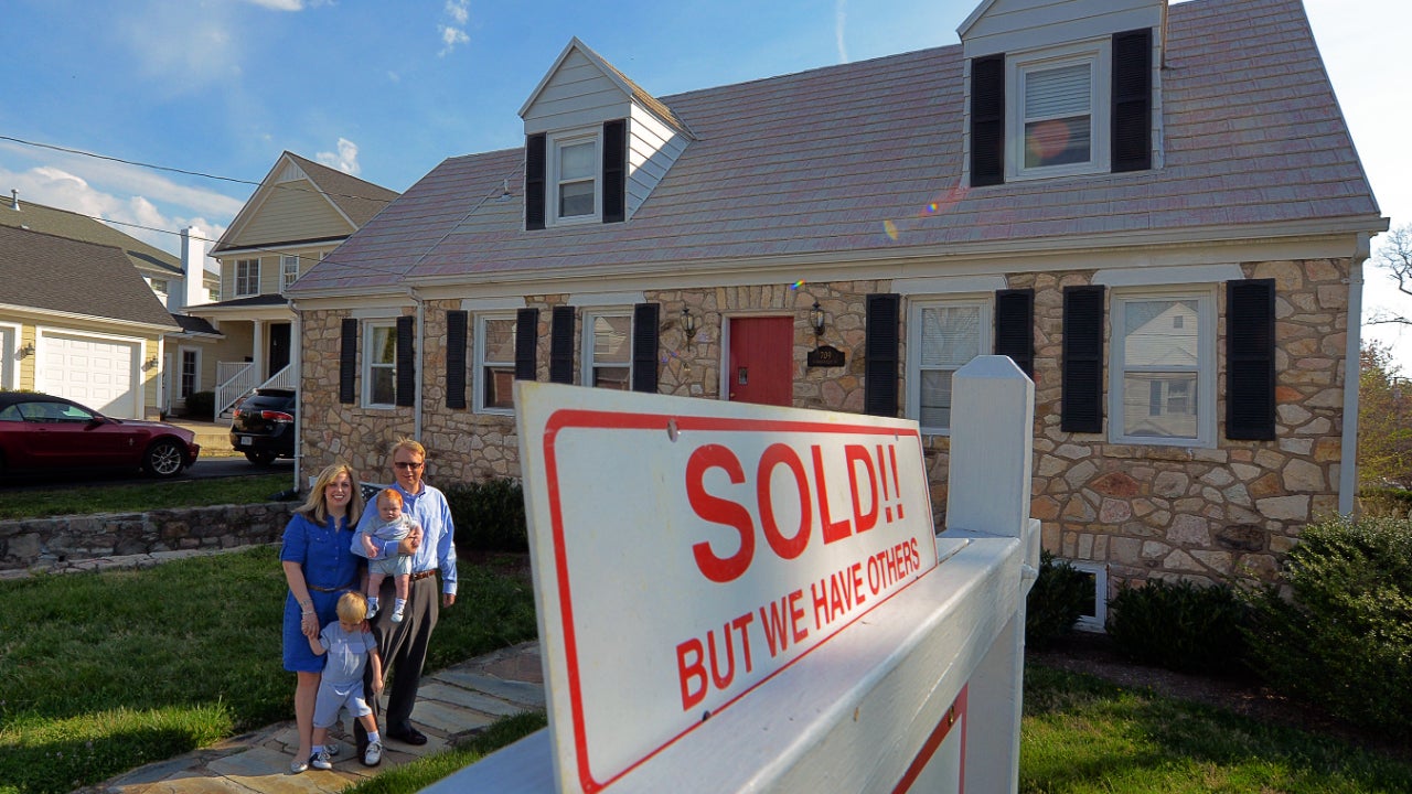 A family stands outside a house they've just purchased
