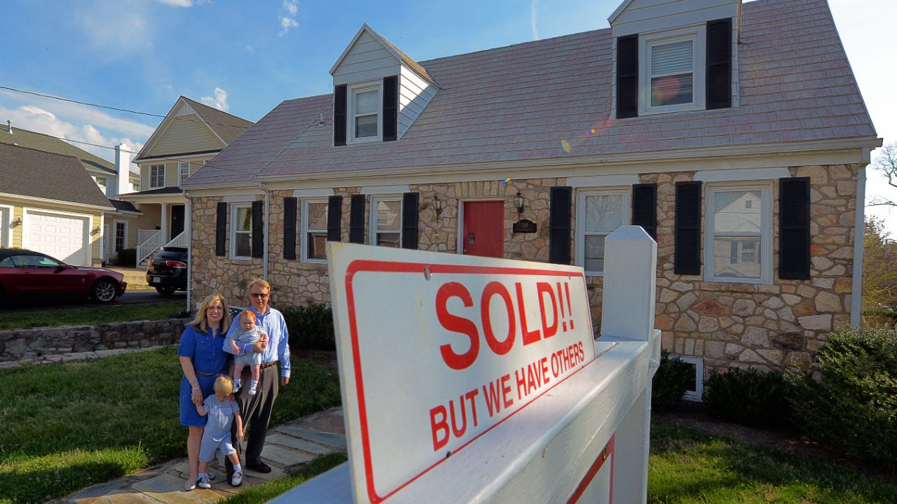 A family stands outside a house they've just purchased