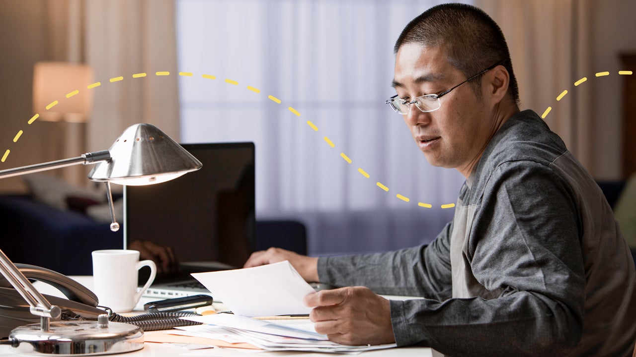 man working on computer and looking at papers