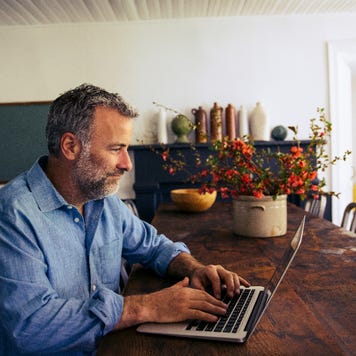 Man sitting at dining room table on laptop