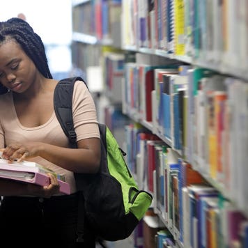 College student looks at books in the library