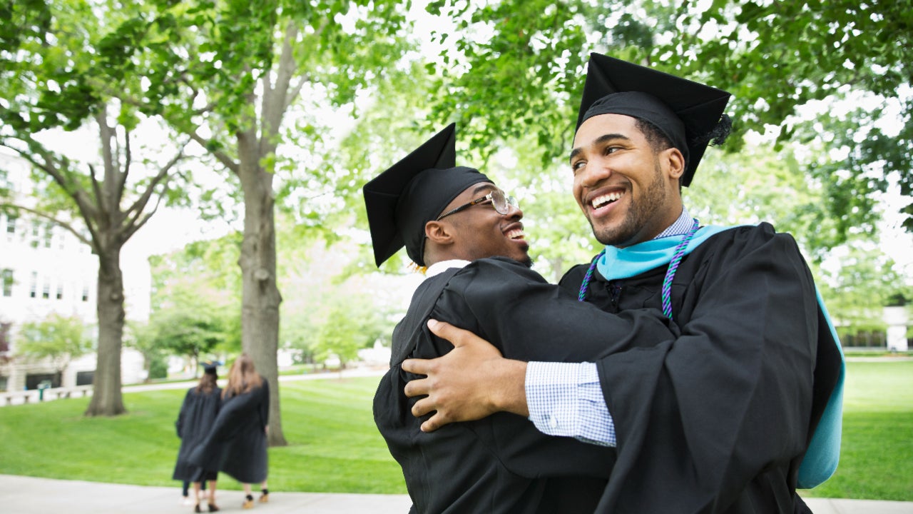 Two college graduates embrace.