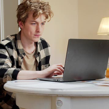Young Man Sitting On Wheelchair Using Laptop