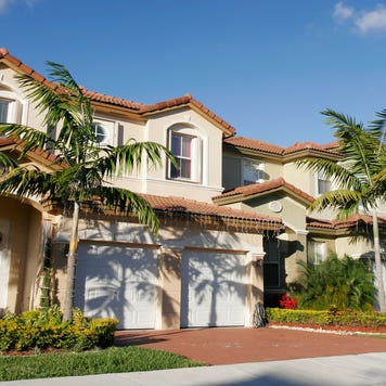 Houses in Florida on a sunny day against the blue sky with palm trees in the front lawn.