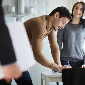 Woman looking at real estate agent while man signing documents at new home