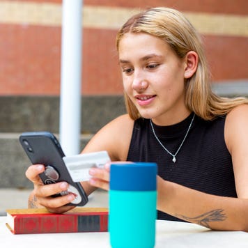 young women on her phone and holding a credit card