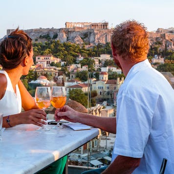 couple cheering glasses overlooking the parthenon in Greece