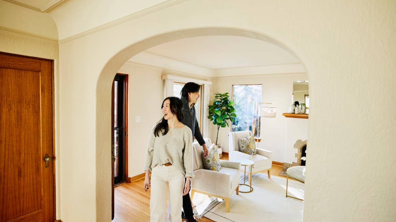 Wide shot of smiling couple walking into home for sale during open house