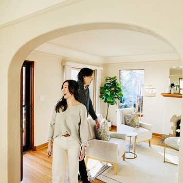 Wide shot of smiling couple walking into home for sale during open house