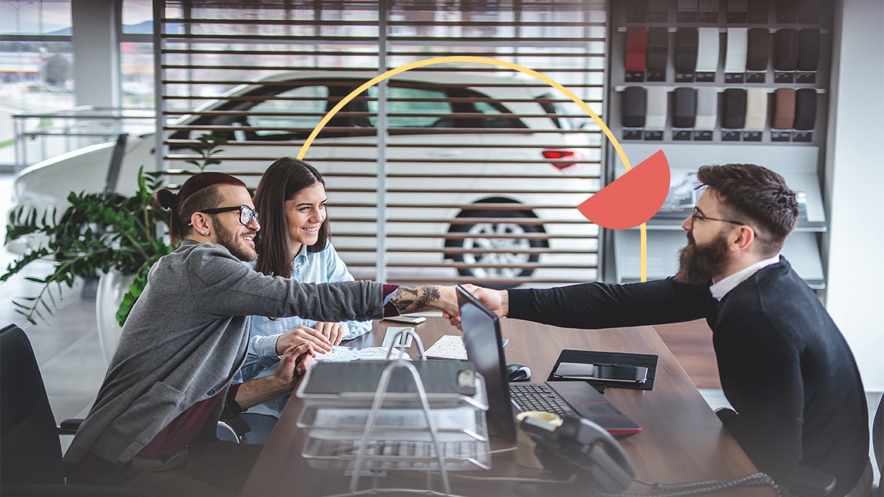 Man and woman sit on the left side of a desk opposite of a car dealership employee. The men are shaking hands across the desk and there is a thin yellow circle illustration behind them with a filled-in orange half circle.