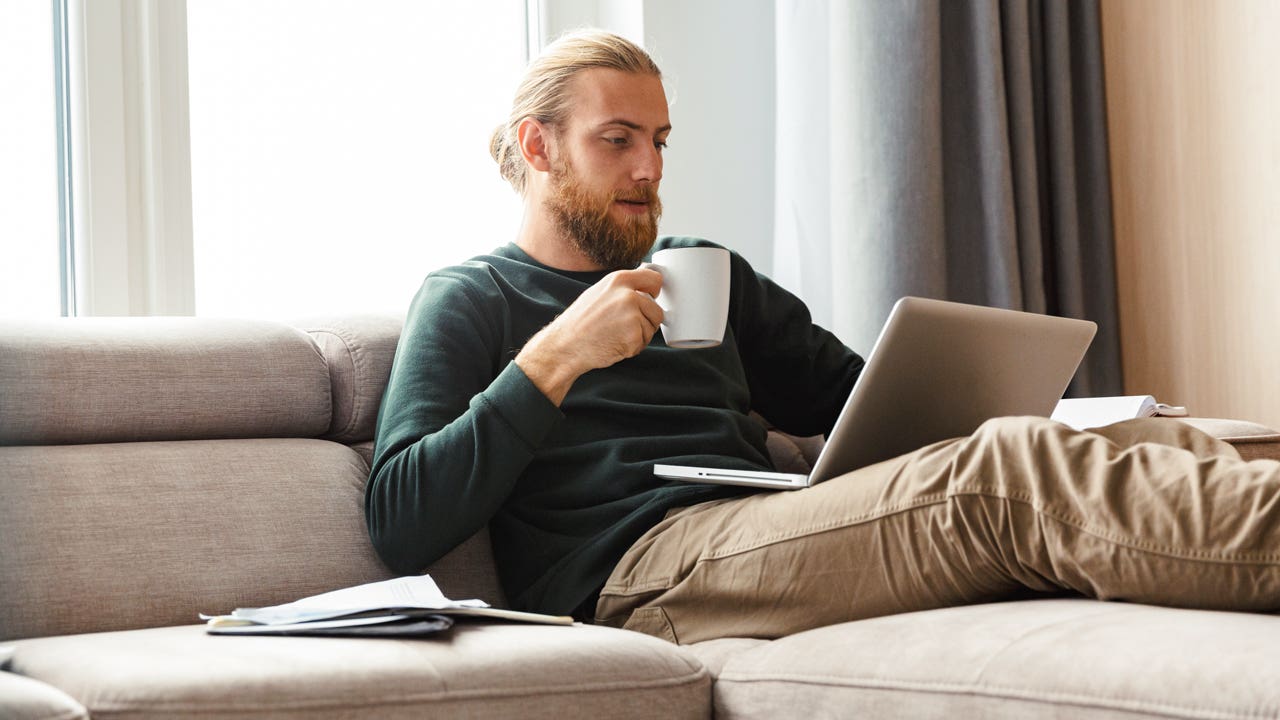 person sitting on the couch and working on laptop