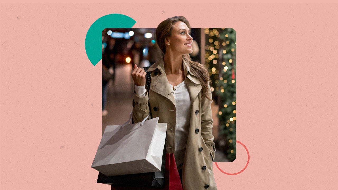 A woman doing Christmas shopping. There is a Christmas tree in the background and they are carrying a couple of shopping bags.