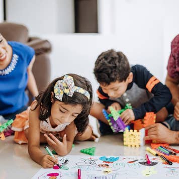 Smiling Hispanic/Latino family - mom, dad, daughter and son - at home drawing pictures and playing games together
