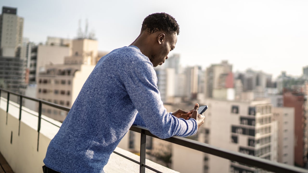 young man using his phone on a city rooftop