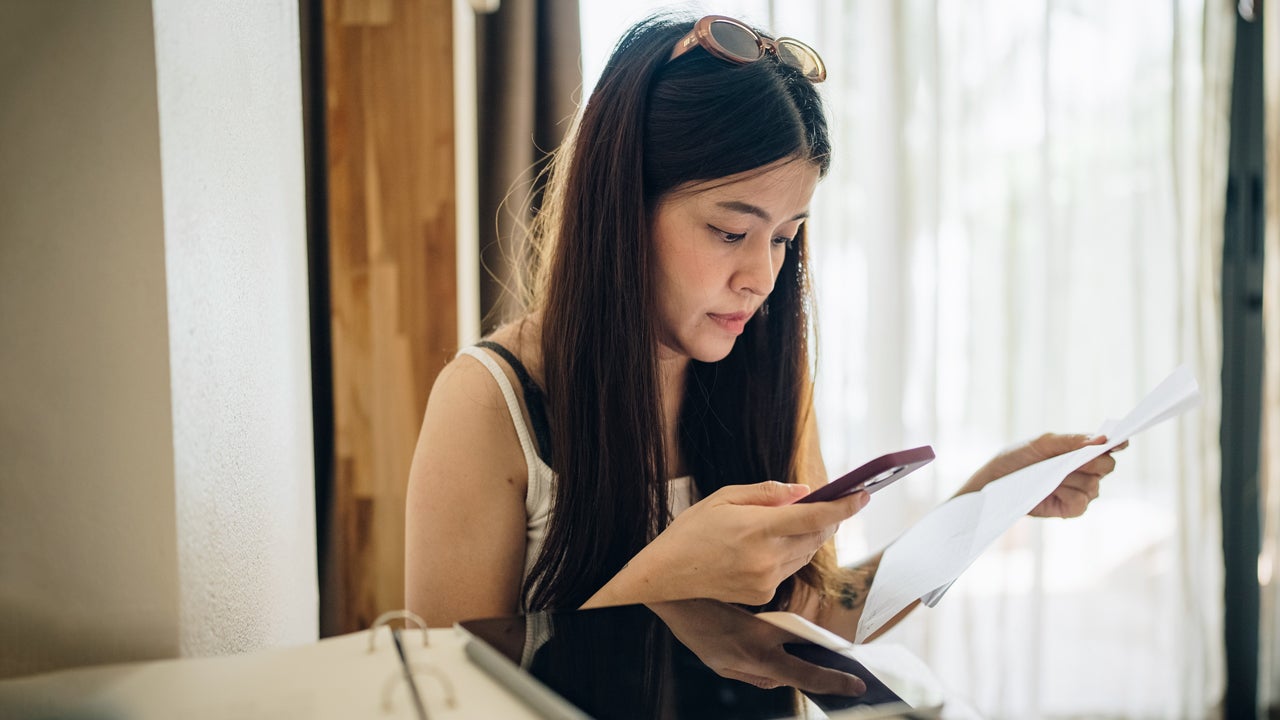 woman looking at her phone and bills