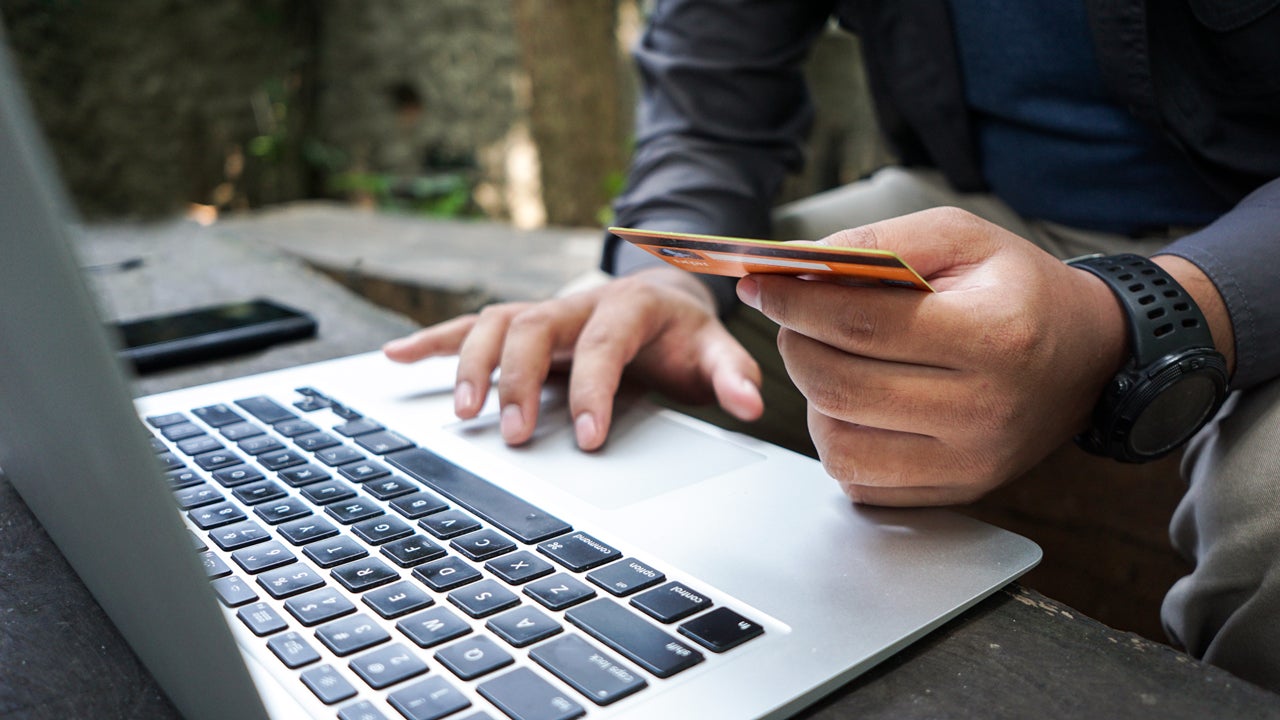 a person holding a card in front of a laptop