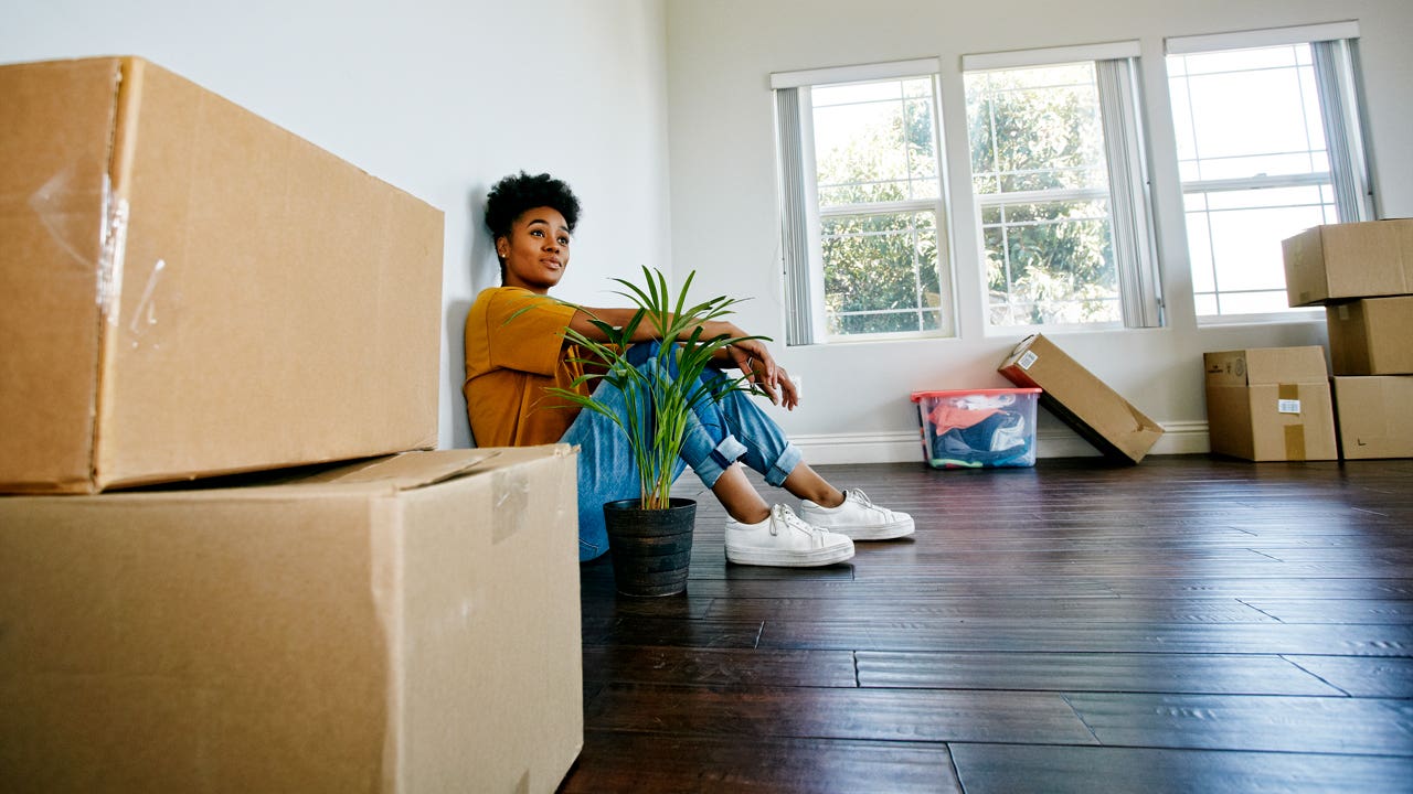 woman sitting on the floor in her new house with boxes around her
