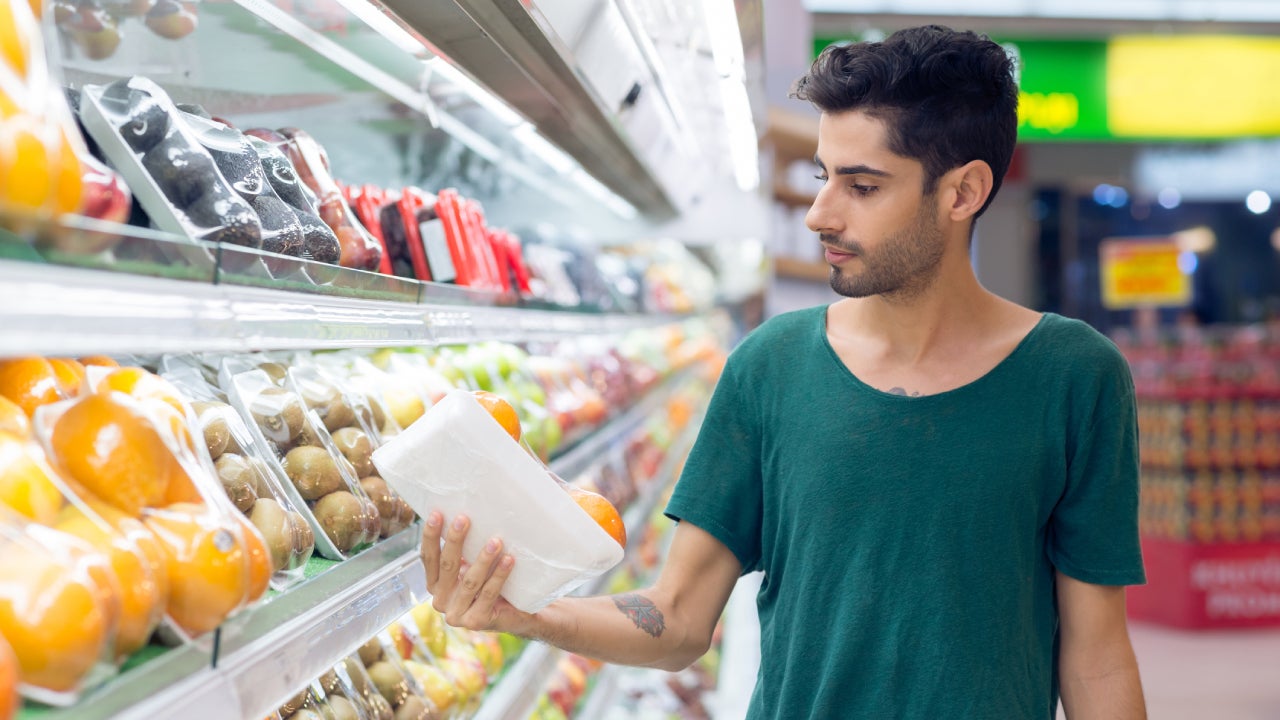 Person shopping at grocery store choosing oranges in the supermarket