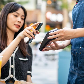 woman paying with her phone at a cafe