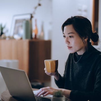 Busy concentrated young woman working from home, working on laptop till late in the evening at home.