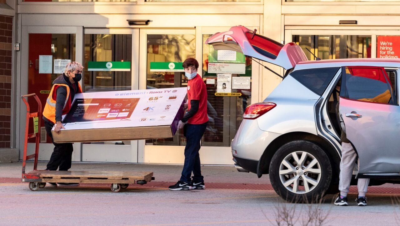 Target employees help a customer put a large screen TV into a vehicle