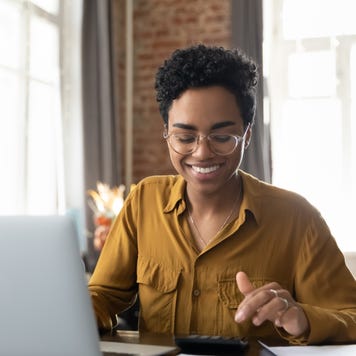 Happy young entrepreneur woman in glasses counting profit