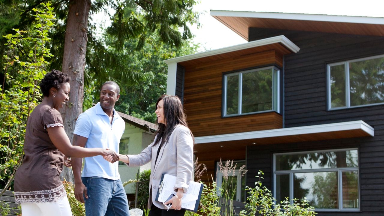 Real estate agent greeting couple at house