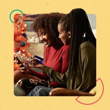 Two women paying for something with a credit card on their cell phone